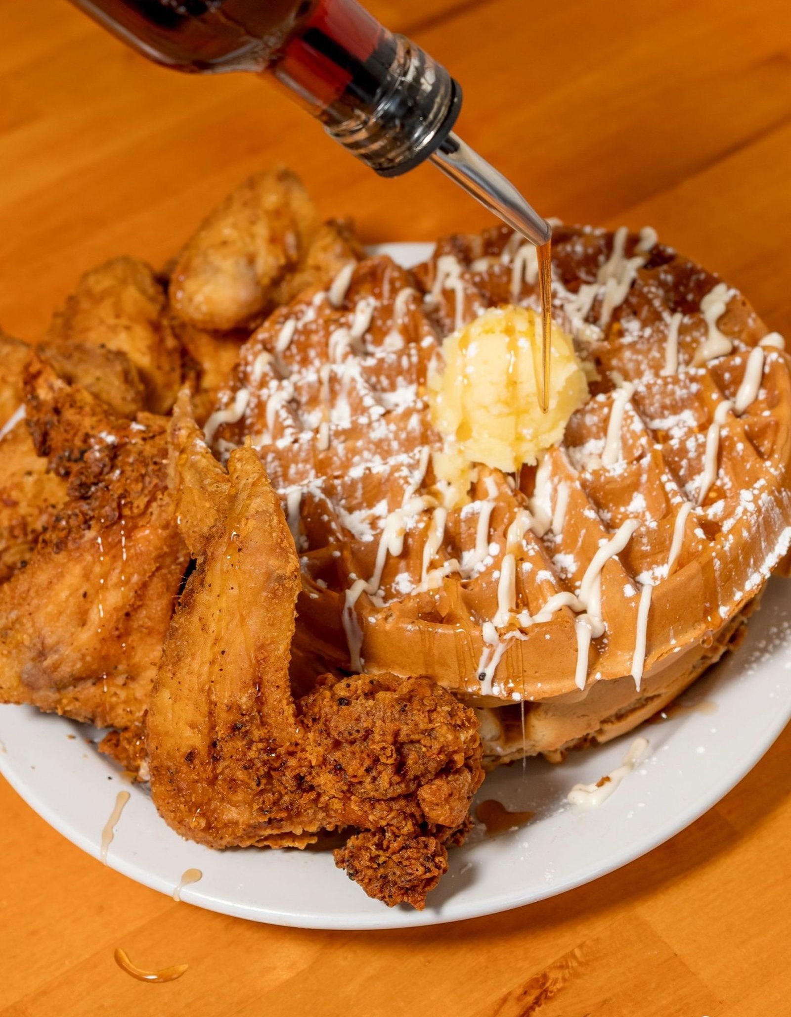Chicken and waffles with syrup being poured over